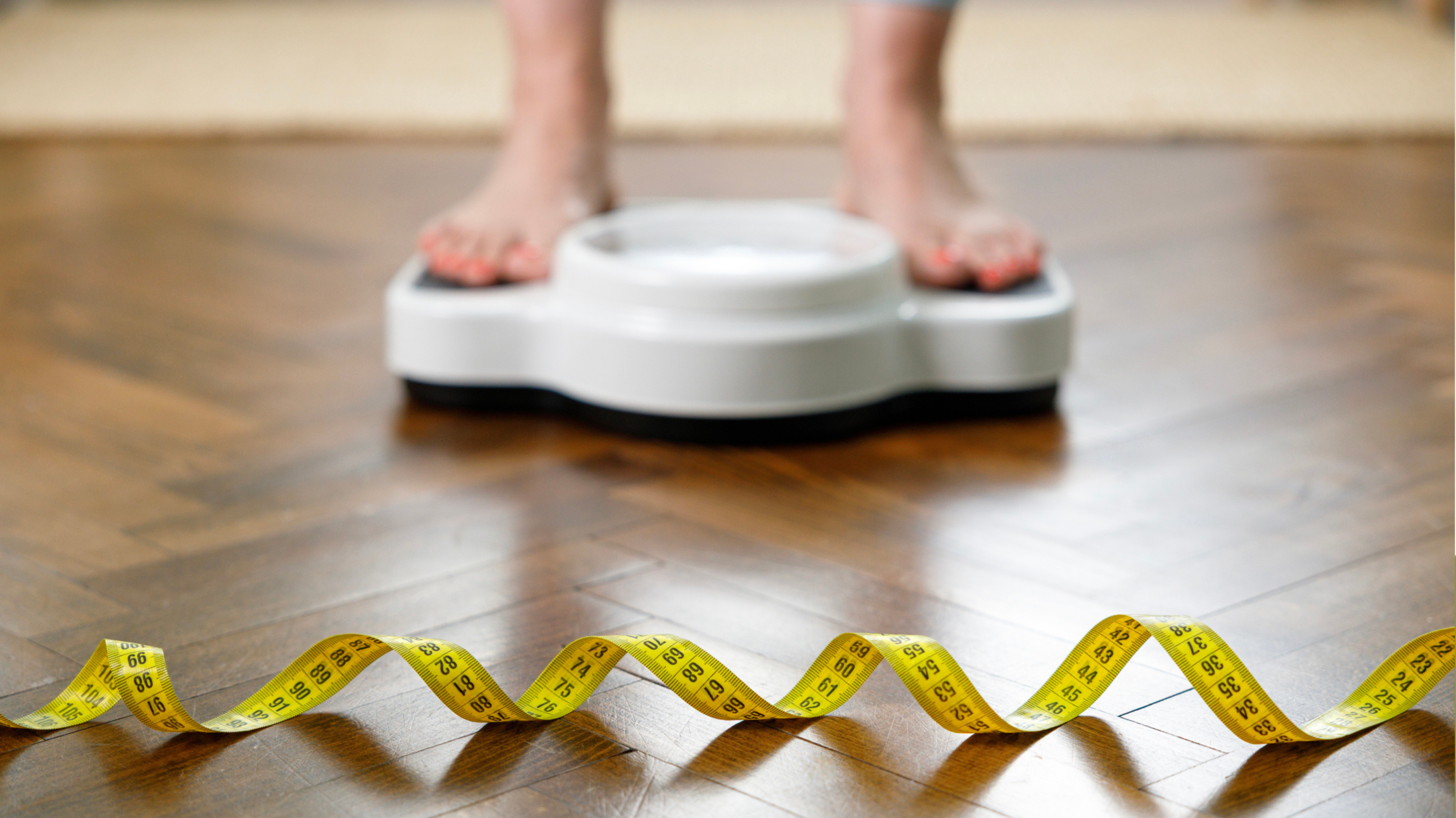 woman on scale worrying about her hormones changing midlife